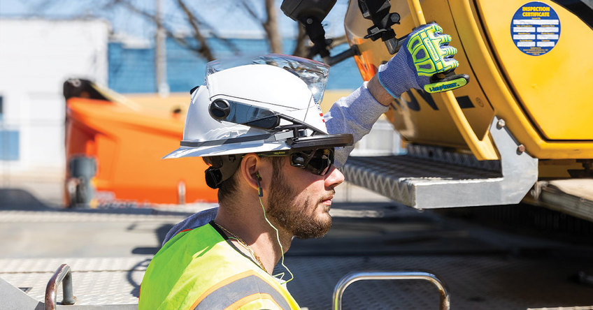Worker on a construction site wearing HexArmor's full brim safety helmet with safety e yewear and hearing protection.